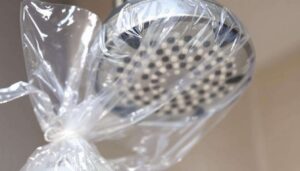 Soffione della doccia pieno di calcare? Il trucco del sacchetto di plastica lo pulisce da solo